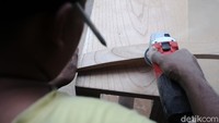 Seorang pekerja melakukan proses penghalusan kayu.
