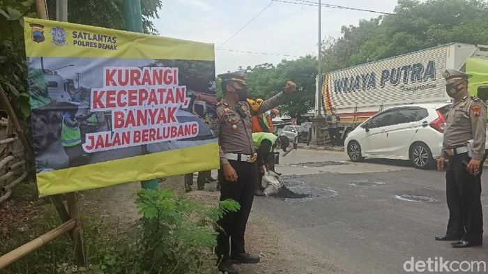 Polisi menandai jalan berlubang dan memasang imbauan bagi pengguna jalan di jalur Pantura Kudus-Semarang, sekitar simpang Desa Jebor, Kecamatan Demak Kota, Demak, Kamis (17/12/2020).