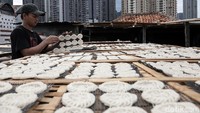 Pekerja membalik kerupuk yang tengah dijemur.