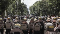 Polisi yang tampak mengenakan atribut lengkap berjaga di area sekitar aksi tersebut.