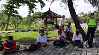 Karena kawasan Pura Tanah Lot terpantau sepi pada pukul 12.00 WITa, para fotografer wisata duduk di bawah pohon karena tak ada wisatawan untuk dipotret. 