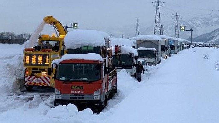 A snowplow (L) clears a path as traffic is seen stuck along the snow-covered Kan-etsu expressway at Minamiuonuma, Niigata prefecture on December 18, 2020. (Photo by STR / JIJI PRESS / AFP) / Japan OUT