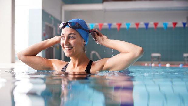 Female Swimmer Wearing Hat And Goggles Training In Swimming Pool