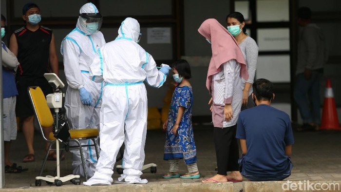 Petugas medis menggunakan Alat Pelindung Diri (APD) memeriksa kondisi pasien COVID-19 yang berstatus OTG (Orang Tanpa Gejala) saat kegiatan berjemur dan olahraga di Stadion Patriot Candrabhaga, Bekasi, Jawa Barat, Senin  (21/12/2020). Kegiatan pemeriksaan kesehatan, berjemur dan berolahraga tersebut rutin dilakukan setiap pagi hari untuk meningkatkan daya tahan tubuh pasien yang menjalani isolasi.
