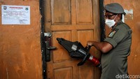 Sejumlah alat dikerahkan untuk membuka gembok pintu kafe ilegal.