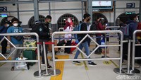 Para penumpang yang antre memasuki stasiun ini membawa barang bawaan tas besar, koper hingga kardus.