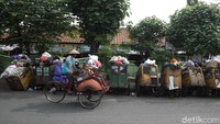 Pengendara becak melintas di depan sampah menumpuk dan berserakan hingga menutupi badan jalan di depan tempat pembuangan sampah sementara Pasar Ngasem, Kota Yogyakarta, Senin (21/12/2020).  