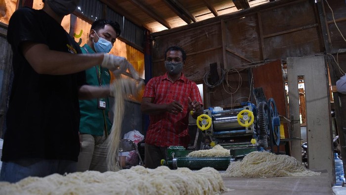 Pegawai Mandiri Syariah (tengah) berbincang dengan nasabah UMKM Suroso (kanan) saat melakukan monitoring produksi mie ayam miliknya di kawasan Depok, Jawa Barat, Selasa (22/12/2020). Mandiri Syariah berkomitmen memberikan dukungan pembiayaan dan pengembangan kepada UMKM baik dalam program langsung maupun melalui kolaborasi dengan program Pemerintah. Komitmen tersebut akan dilanjutkan dan dijalankan oleh bank hasil penggabungan pada tahun 2021, dimana bank syariah penggabungan memiliki target penyaluran UMKM sebesar 23 persen atau di atas ketentuan OJK sebesar 20 persen. ANTARA FOTO/Indrianto Eko Suwarso