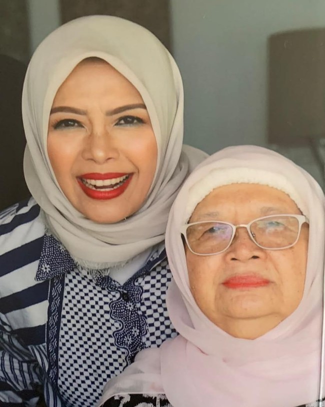 Ibu dari tiga anak ini kerap menggunakan hijab segiempat untuk sehari-hari. Seperti dalam foto ini, Mpok Nur yang berpose dengan sang ibunda, memakai bahan hijab voal rawis warna nude yang ia lilit rapi ke belakang.  Foto: Instagram @nurasiauno.