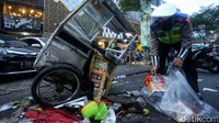 Polisi tampak mengumpulkan beragam barang di sekitar gerobak makanan yang ringsek usai ditabrak mobil.