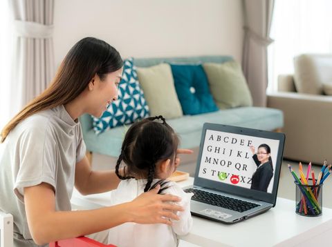 Asian kindergarten school girl with mother video conference e-learning with teacher on laptop in living room at home. Homeschooling and distance learning ,online ,education and internet.