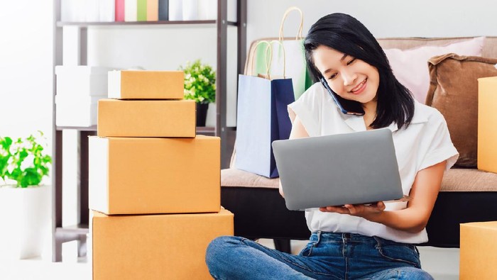 Asian beautiful woman working with laptop and smartphone to online business shop at home.Owner businesswoman start up with Accept orders,Check the products, Prepare to deliver products to customers.