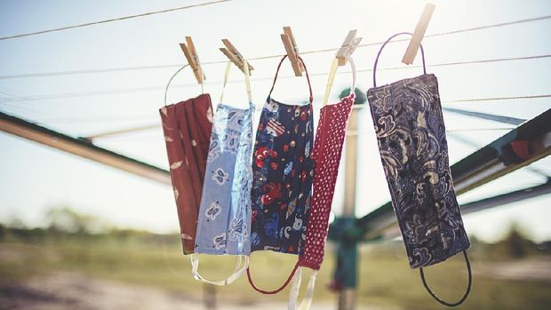 Ilustrasi masker kain Self-sewn mouth-nose masks against corona viruses hang on the clothesline to dry.