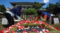 Para peziarah menaburkan bunga di makam keluarga.