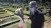 Warga berziarah ke makam dengan membawa bunga. Protokol kesehatan juga diterapkan saat berziarah di makam keluarganya.
