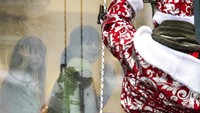Santa Klaus menghibur pasien anak-anak dari balik jendela kaca rumah sakit.