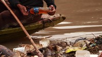 Terlihat, seorang warga dengan menaiki perahu memungut sampah yang masih dapat dijual dan dimanfaatkan.
