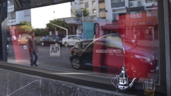 FILE - In this Monday, March 16, 2020 file photo, a glass of Moroccan tea is left by a window of a closed down coffee shop, after the Moroccan government announced further restrictions to avoid the spread of coronavirus, including closure of cafes and mosques, in the capital Rabat, Morocco. Morocco has imposed a curfew, closed restaurants in major cities and banned public and private gatherings for three weeks — including the usually festive New Years Eve — to curb the spread of the virus.The curfew between 9 p.m and 6 a.m went into effect Wednesday, Dec. 23, 2020 and is set to last until Jan. 13.  (AP Photo/Mosaab Elshamy, File)