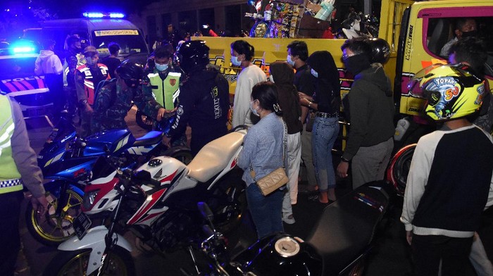 Sejumlah pelanggar protokol kesehatan mendapatkan sanksi menyapu jalan usai terjaring patroli penegakkan protokol kesehatan di Pos Polisi Bundaran HI, Jakarta, Sabtu (26/12/2020). Patroli gabungan dilakukan untuk menertibkan warga yang berkerumun saat jam malam untuk selanjutnya di uji rapid test, menyusul meningkatnya penyebaran COVID-19 di Ibu kota. ANTARA FOTO/Indrianto Eko Suwarso/rwa.