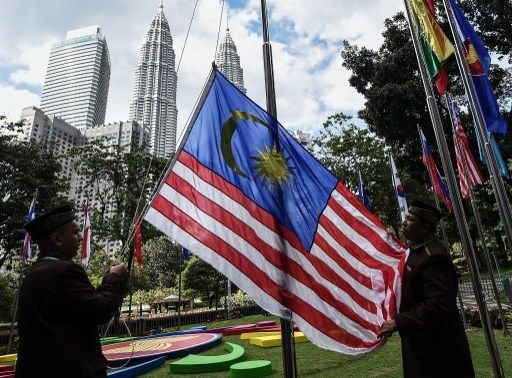 Workers put up a Malaysian flag ahead of the 27th Association of Southeast Asian Nations (ASEAN) Summit at the Kuala Lumpur convention center on November 18, 2015.  Malaysia will host the 27th ASEAN summit from November 18-22.    AFP PHOTO / MANAN VATSYAYANA (Photo by MANAN VATSYAYANA / AFP)