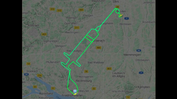 Ajak Orang Vaksinasi COVID-19, Pilot Gambar Alat Suntik Raksasa di Udara