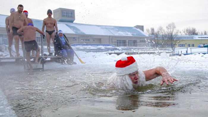 A man dressed as a Ded Moroz (Santa Claus, or Father Frost) swims in the ice cold water during a frosty day in Siberian city of Omsk, Russia, Saturday, Dec. 26, 2020. The temperature in Omsk dropped down to -32 degree Celsius (-25,6 degree Fahrenheit). (AP Photo/Evgeniy Sofiychuk)