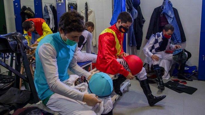 Pacuan Kuda di Spanyol Tetap Bertahan di Tengah Pandemi Turf horse race aficionados follow a race at the Hipodromo de la Zarzuela outskirts of Madrid, Spain, Sunday, Dec. 6, 2020. The pandemic may have altered many habits but horse racing at the Zarzuela has changed little. (AP Photo/Bernat Armangue)
