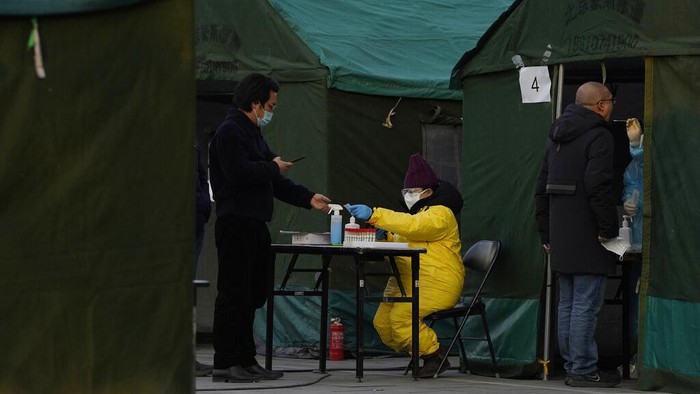 Residents line up for coronavirus tests at tents set up on the streets of Beijing on Sunday, Dec. 27, 2020. Beijing has urged residents not to leave the city during the Lunar New Year holiday in February, implementing new restrictions and mass testings after several coronavirus infections last week. (AP Photo/Ng Han Guan)