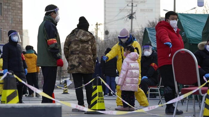 Residents line up for coronavirus tests at tents set up on the streets of Beijing on Sunday, Dec. 27, 2020. Beijing has urged residents not to leave the city during the Lunar New Year holiday in February, implementing new restrictions and mass testings after several coronavirus infections last week. (AP Photo/Ng Han Guan)