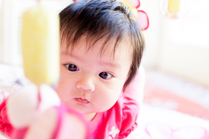 mata juling A cute Asian/Eurasian baby girl is fixated on a hanging mobile toy. Her eyes are slightly crossed as she examines it. She is just over 1 years old.