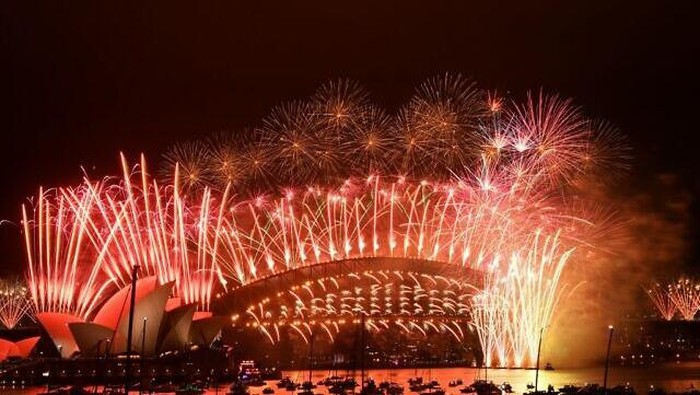 Kembang api Malam Tahun Baru meletus di atas Harbour Bridge dan Opera House (kiri) Sydney yang ikonik selama pertunjukan kembang api pada 1 Januari 2021. (Foto oleh SAEED KHAN / AFP)