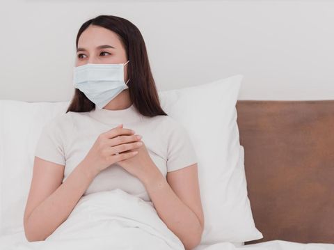 Asian woman wearing mask, sick doctor, cough, use to grasp the chest in the bedroom