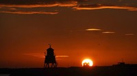 Matahari terbit di atas groin yang membentuk siluet di South Shields, di pantai Timur Laut Inggris. AP Photo/Owen Humphreys.