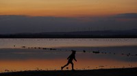 Seorang gadis kecil berlari di danau garam saat matahari terbenam di kota pesisir selatan Larnaca, Siprus. AP Photo/Petros Karadjias.