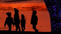 Siluet anak-anak di kolam saat mereka melihat lampu Natal di sebuah taman di Lenexa, Kansas. AP Photo/Charlie Riedel.