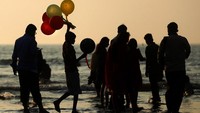 Seorang anak laki-laki menjual balon di pantai Juhu yang ramai di Mumbai, India. AP Photo/Rafiq Maqbool.