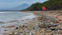 Wisatawan berjalan melewati sampah kiriman yang memenuhi pesisir Pantai Kuta, Badung, Bali, Kamis (31/12/2020).
