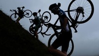 Atlet pesepeda menenteng sepedanya saat mendaki bukit di Settle, Inggris. Ian Forsyth/Getty Images  
