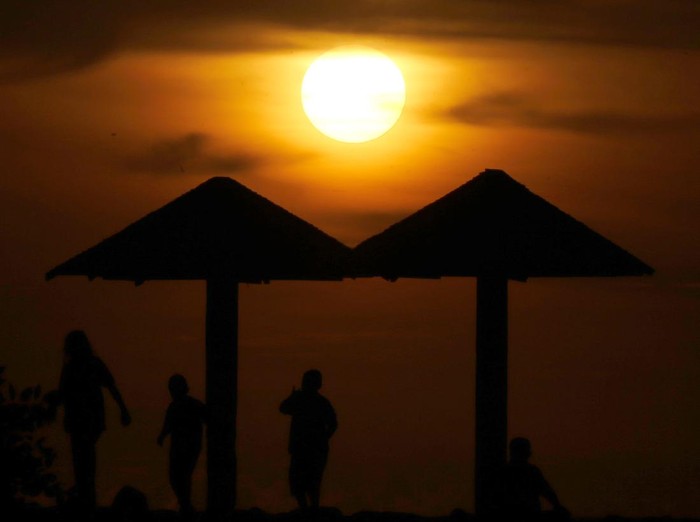 Warga menikmati panorama alam matahari terbenam (sunset) akhir tahun 2020 di pantai Babah Kuala Lampuuk, Aceh Besar, Aceh, Kamis (31/12/2020). Menikmati sunset di provinsi paling ujung barat pulau Sumatera menjadi wisata alternatif bagi sebagian warga setelah adanya larangan perayaan pergantian tahun masehi di provinsi Aceh. ANTARA FOTO/Irwansyah Putra/rwa.