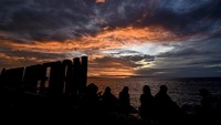 Berbeda lagi dengan masyarakat di Mataram, Lombok, NTB ini. Warga menikmati matahari terbenam (sunset) pada hari terakhir tahun 2020 di Pantai Ampenan, Mataram, NTB, Kamis (31/12/2020). ANTARA FOTO/Ahmad Subaidi