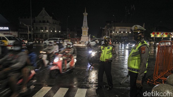 Petugas gabungan dari Kepolisian dan Satuan Polisi Pamong Praja berjaga pada malam pergantian tahun di simpang empat Tugu Pal Putih, Yogyakarta, Kamis (31/12/2020). Pemerintah Daerah Istimewa Yogyakarta (Pemda DIY) menutup tempat wisata saat malam pergantian tahun. Penutupan itu menyasar empat kabupaten di DIY. Penutupan itu tertuang dalam surat nomor 443/03734 tentang penutupan objek wisata pada malam pergantian tahun baru. Surat tertanggal 31 Desember yang diteken Sekda DIY Kadarmanta Baskara Aji ini ditujukan ke Bupati Sleman, Bupati Bantul, Bupati Gunungkidul dan Bupati Kulonprogo. detikcom/Pius Erlangga