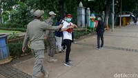 Beberapa warga lainnya datang bergerombol dan langsung ditegur petugas.