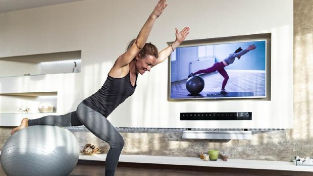 aktivitas olahraga saat pandemi Happy athletic woman exercising during live streaming sports training over television in the living room.