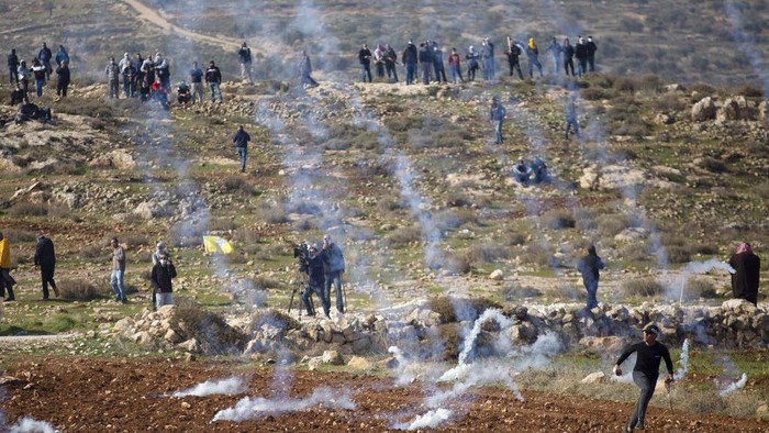 Palestinian protesters use slingshots to hurl stones towards Israeli troops during a protest against Israeli settlements, in the West Bank village of Deir Jarir, north of Ramallah, Friday, Jan. 1, 2021. (AP Photo/Majdi Mohammed)
