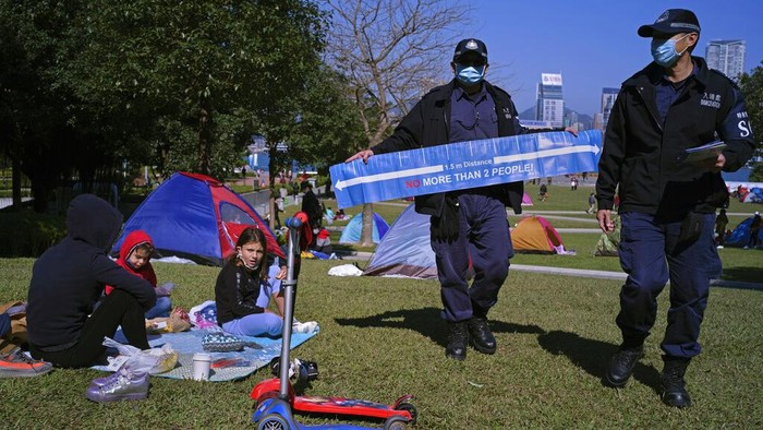 A police officer displays a banner showing social distancing to prevent the spread of coronavirus at a park in Hong Kong Saturday, Jan. 2, 2021. (AP Photo/Vincent Yu)