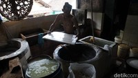 Seorang perajin bersiap melakukan pemotongan tahu sebelum dijual ke pasaran.
