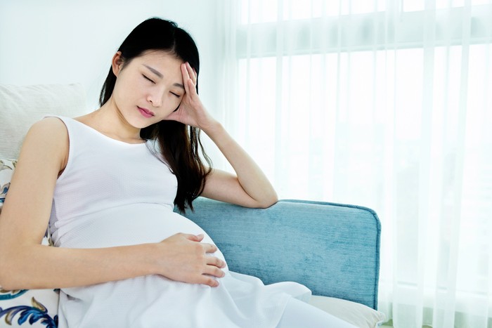 hamil Pregnant woman sitting on sofa and having headache