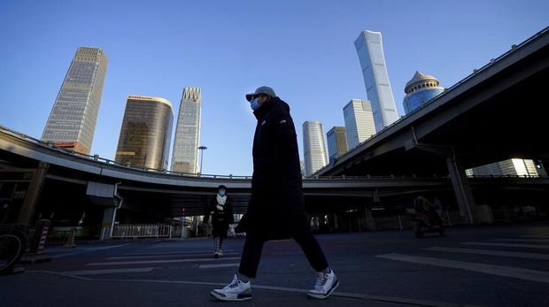 People wearing face masks to help curb the spread of the coronavirus walk through commercial office buildings in Beijing, Monday, Jan. 4, 2021. Wary of another wave of infections, China is urging tens of millions of migrant workers to stay put during next month's Lunar New Year holiday, usually the world's largest annual human migration. (AP Photo/Andy Wong)