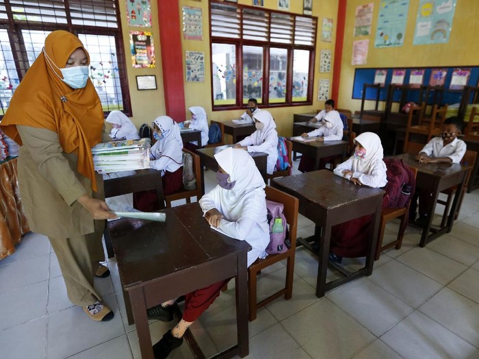 Pelajar membenahi masker adiknya pada hari pertama sekolah tatap muka di SD Negeri 42, Banda Aceh, Aceh, Senin (4/1/2021). Mayoritas lembaga pendidikan tingkat SD, SMP, dan SMA di provinsi Aceh mulai melaksanakan pembelajaran tatap muka dengan sistim bergiliran dan menerapkan protokol kesehatan secara ketat untuk mencegah penularan COVID-19. ANTARA FOTO/Irwansyah Putra/hp.