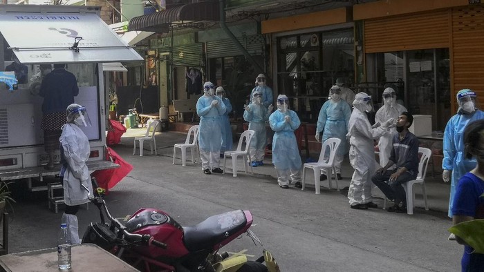 FILE - In this Dec. 20, 2020, file photo, a health worker in protective clothing collects nasal swab sample from a man to test for COVID-19 in Samut Sakhon, south of Bangkok. Thailand, which has kept the coronavirus largely in check for most of the year, is facing a challenge from a large outbreak of the virus among migrant workers in the province close to Bangkok.(AP Photo/ Chalida Ekvitthayavechnukul, File)